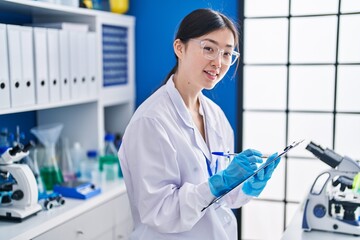 Chinese woman scientist writing on document at laboratory