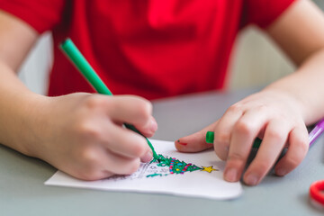 a child at a table paints a Christmas tree