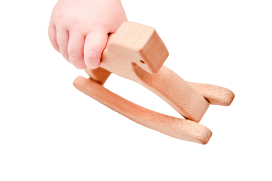 Baby hand and toy wooden rocking horse, close-up, isolated on a white background. Children fingers and an object on a white background