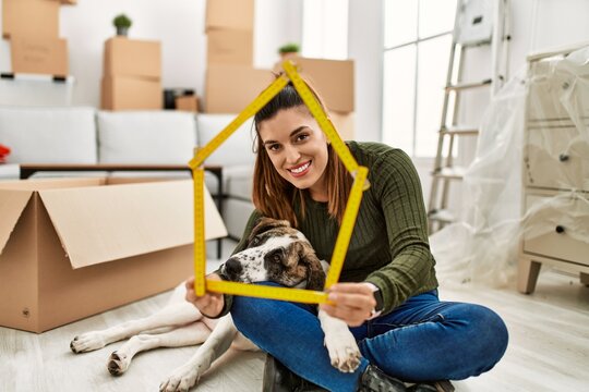 Young woman smiling confident holding house project sitting with dog at home