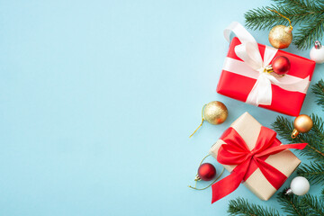 Christmas composition with holiday decorations on blue. Fir tree, present box and decor. Top view with copy space..