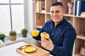 Fototapeta na wymiar Young latin man having breakfast sitting on table at home