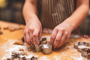 girl makes ginger cookies with Christmas cookie forms