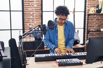 Young hispanic man musician playing piano keyboard at music studio - Powered by Adobe