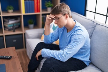 Young caucasian man stressed sitting on sofa at home