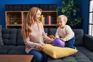 Mother and son playing with ball sitting on sofa at home