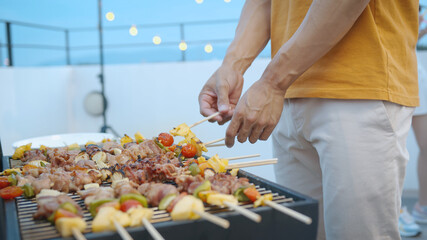Happy asian man with friends in barbecue dinner party and enjoying meal together.