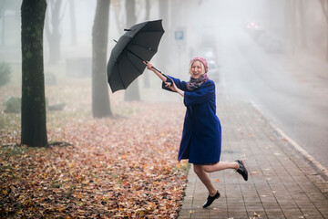A cheerful woman with an umbrella in foggy weather.