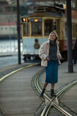 Obraz premium A woman stands near a vintage streetcar.