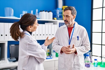 Middle age man and woman scientists having conversation at laboratory