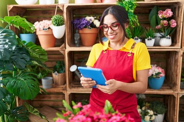 Young beautiful arab woman florist smiling confident using touchpad at flower shop