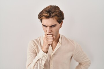 Young man standing over isolated background feeling unwell and coughing as symptom for cold or...