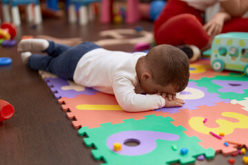 Adorable toddler lying on floor crying at kindergarten