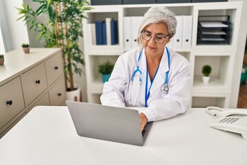 Middle age woman wearing doctor uniform working at clinic