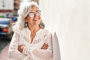 Middle age woman smiling confident standing with arms crossed gesture at street