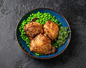 Baked Chicken thighs with green peas in blue plate