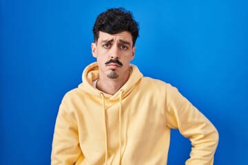 Hispanic man standing over blue background depressed and worry for distress, crying angry and afraid. sad expression.