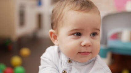 Adorable toddler standing with serious expression at kindergarten