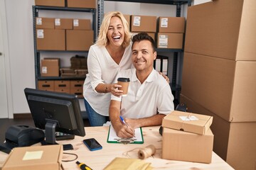 Middle age man and woman business partners drinking coffee working at storehouse