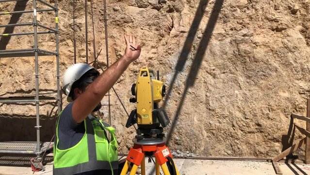 Geodetic or topographic works at construction site. Land surveyor doing a measurements on total station. Topographer looks to theodolite telescope