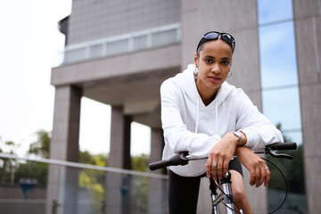 Portrait of stylish african american woman looking at camera near bicycle on street 