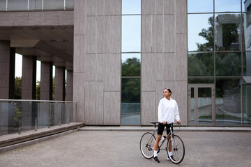 Stylish african american woman looking away near bike on city street 