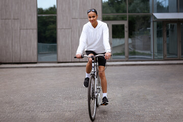 Fit african american woman looking at camera while riding bicycle on street 