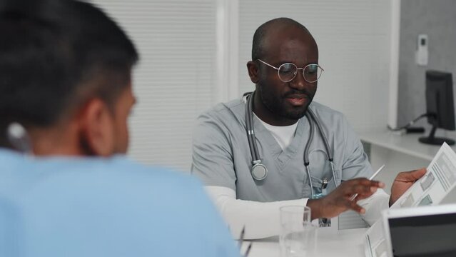 Group Of Ethnically Diverse Medical Students Or Interns Sitting At Table Working On Project Discussing Work Plan, Selective Focus Shot