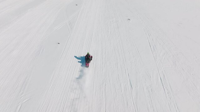 Drone of woman riding snowmobile in arctic