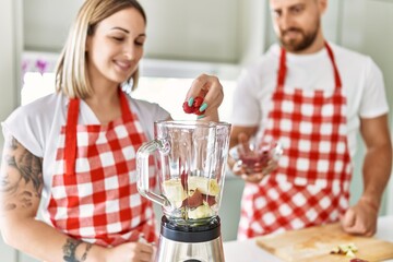 Young couple smiling confident making smoothie cooking at kitchen