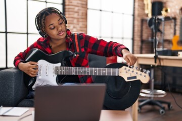 African american woman musician having online electrical guitar lesson at music studio