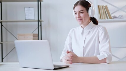 Online interpreter. Virtual call. Remote coaching conference. Enthusiastic woman in headphones speaking using laptop at light modern home office interior. Long video shot.