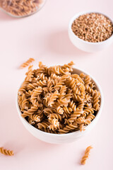 Bowls with raw buckwheat pasta and groats on the table. Alternative to wheat. Vertical view