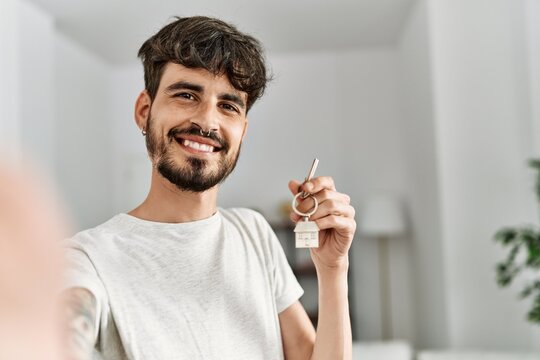 Young hispanic man making selfie by the camera holding key of new home