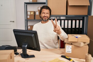 Handsome middle age man working at small business ecommerce smiling looking to the camera showing...