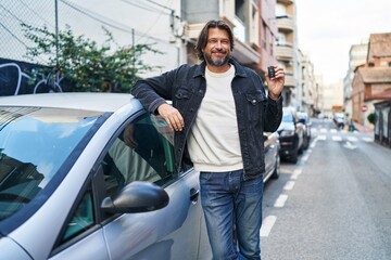 Middle age man smiling confident holding key of new car at street