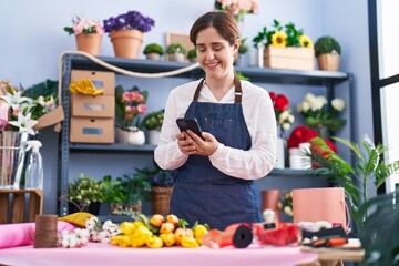 Young woman florist smiling confident using smartphone at florist shop