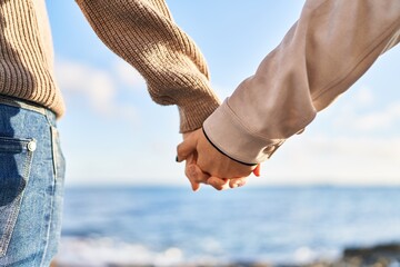 Man and woman couple standing on back view with hands together at seaside