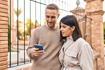 Man and woman couple smiling confident using smartphone at street