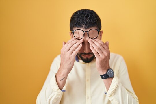 Hispanic young man wearing business clothes and glasses rubbing eyes for fatigue and headache, sleepy and tired expression. vision problem