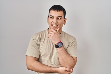 Young arab man wearing casual t shirt with hand on chin thinking about question, pensive expression. smiling and thoughtful face. doubt concept.