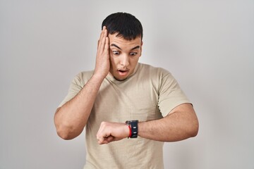 Young arab man wearing casual t shirt looking at the watch time worried, afraid of getting late