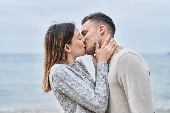 Man and woman couple hugging each other kissing at seaside