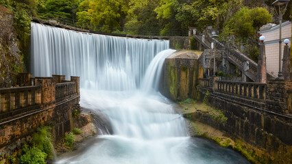 The most beautiful waterfall in New Athos surrounded by ancient walls. Waterfall with blurred water movement.