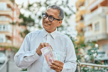 Middle age southeast asian man holding indian rupees banknotes at the city