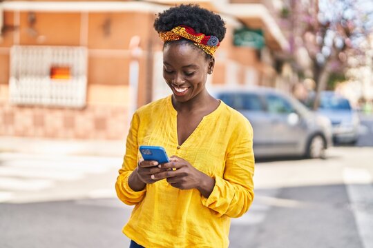 Young african american woman smiling confident using smartphone at street