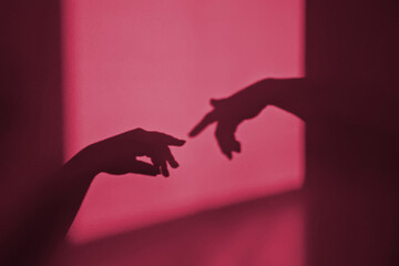 Abstract shadow silhouette of gesture touch by humans palms from sunbeam on wall. Image toned in...