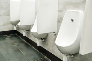 a row of white urinals in the men's room, a row of urination spots