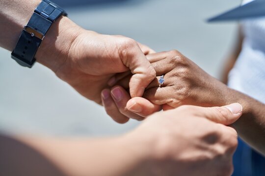 Man and woman interracial couple with hands together showing egagement ring at street - Powered by Adobe