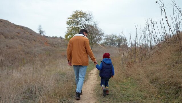 Pretty father and son walking on the slope in the fall